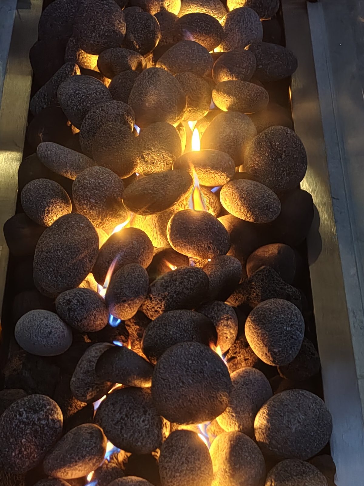 Close-up of lava stones and the stainless steel burner in a custom gas fire pit